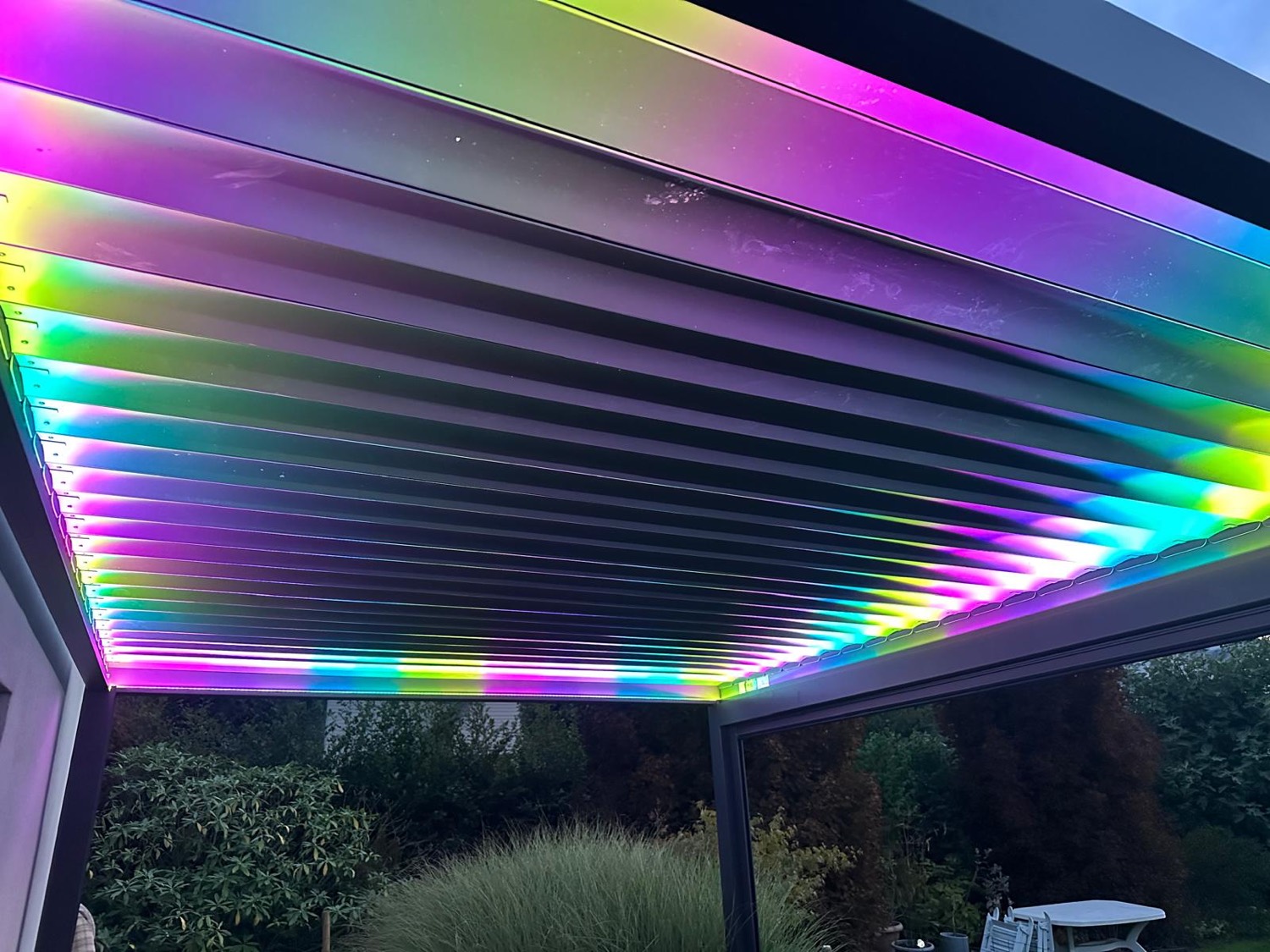 Détail des lames de la pergola illuminées par un bandeau LED RGB multicolore la nuit