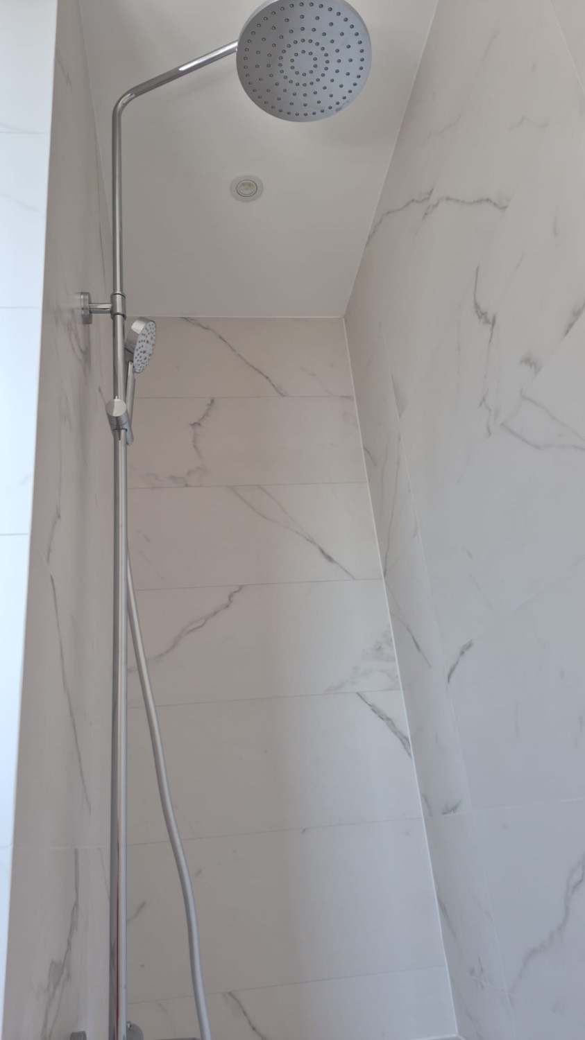 Douche à l'italienne avec colonne de douche et faïence effet marbre blanc veiné