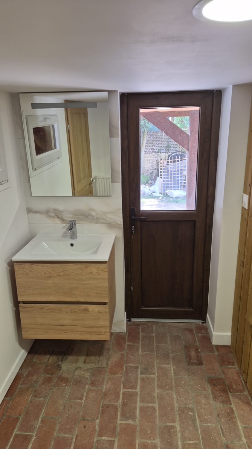 Salle d'eau avec meuble vasque et porte vitrée en bois donnant sur le jardin