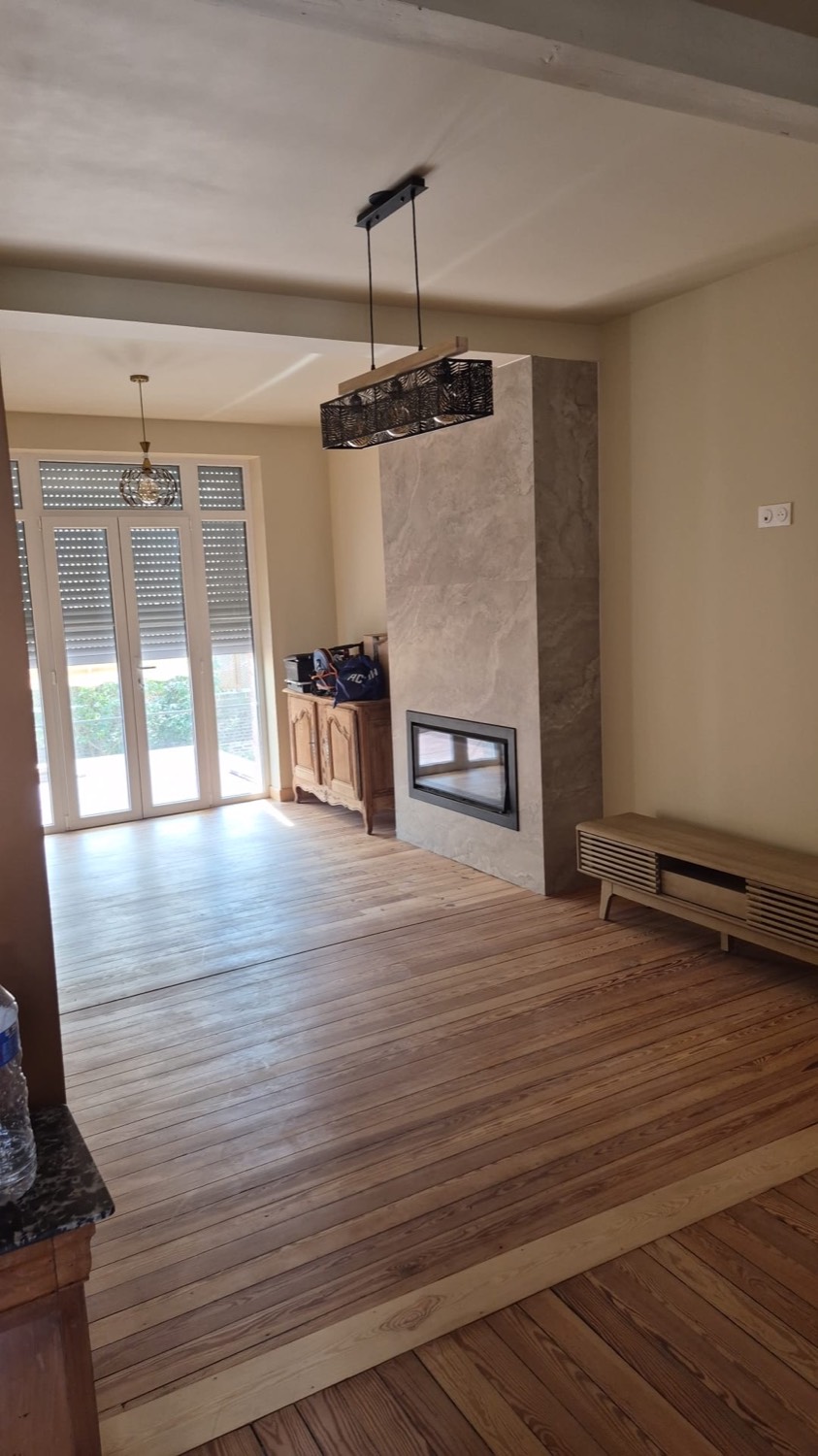 Séjour rénové avec cheminée à insert habillée de pierre et parquet ancien restauré