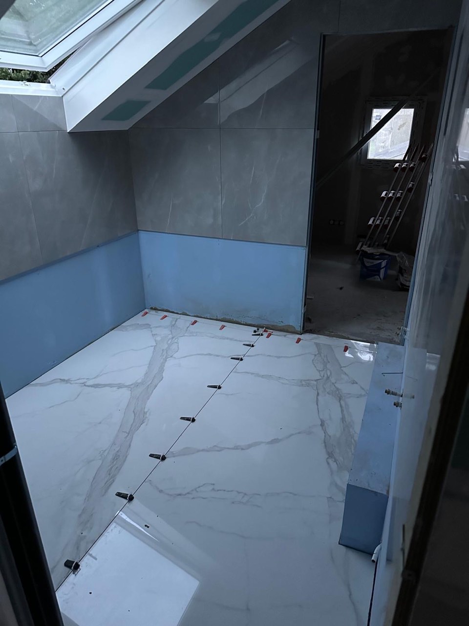 Avant : la salle de bain de Lisieux en chantier, carrelage en cours de pose sous la fenêtre de toit