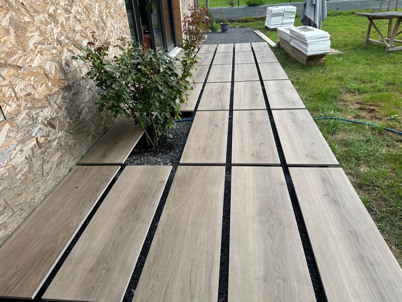 Terrasse en dalles carrelées grand format effet bois posées sur plots le long de la façade d'une maison — chantier à Villerville