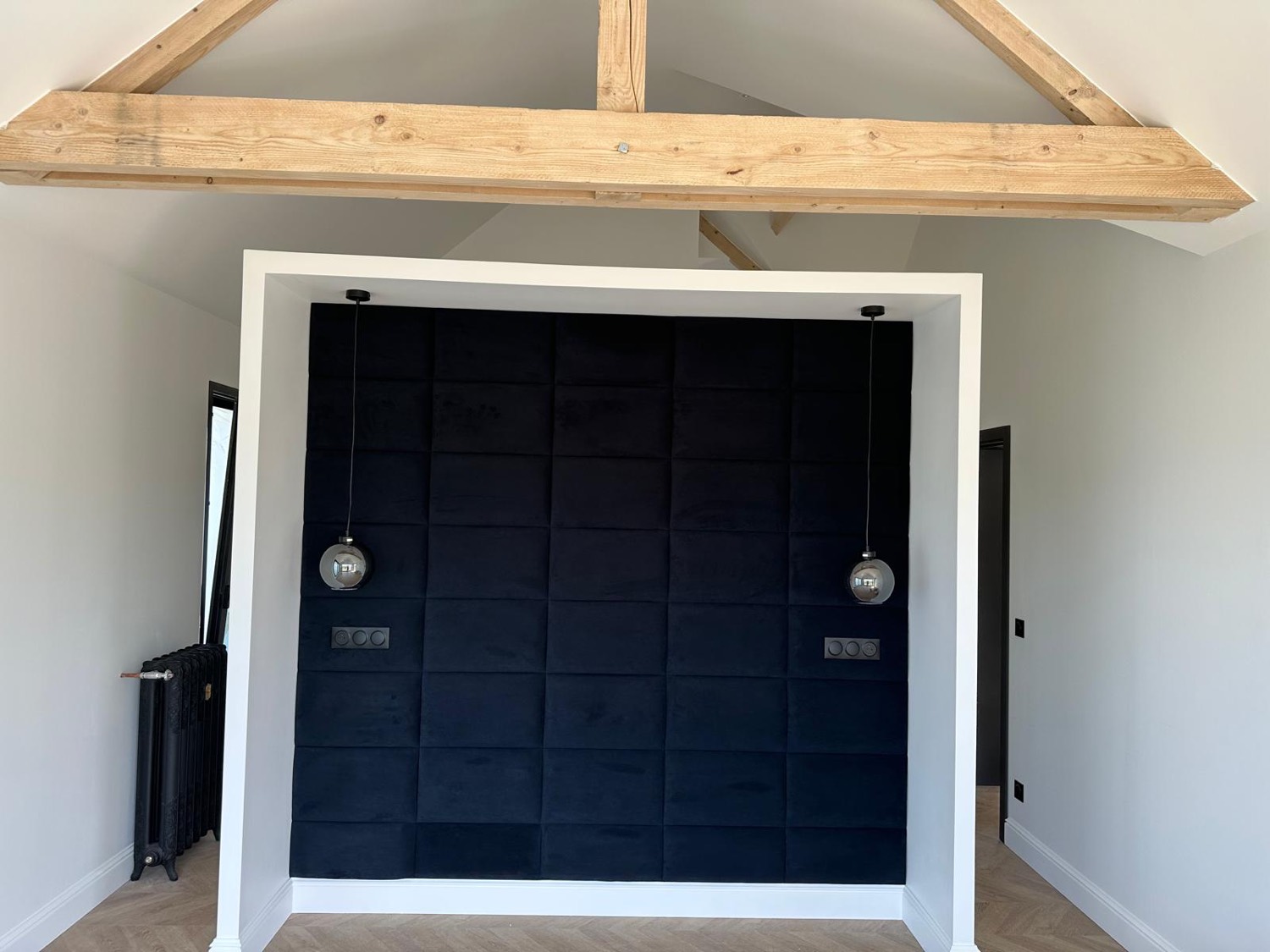 Chambre avec tête de lit capitonnée en velours bleu nuit sous poutres bois apparentes