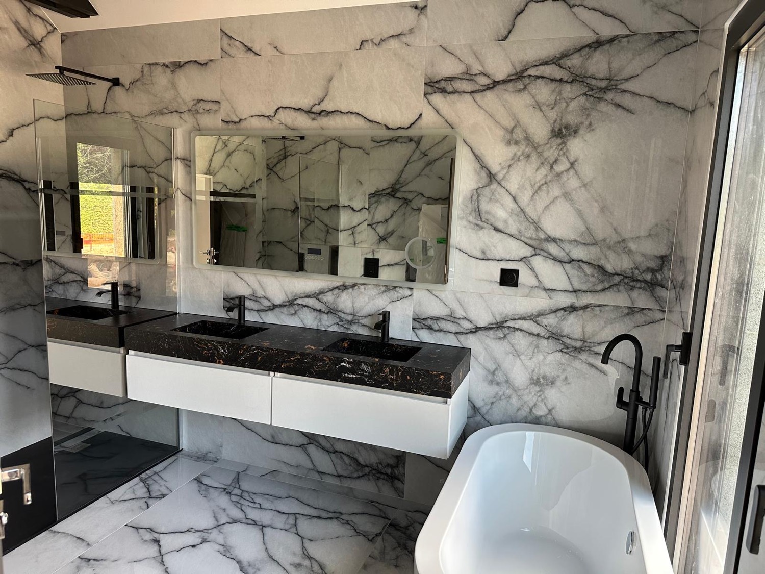 Salle de bain en marbre blanc veiné avec double vasque pierre foncée et baignoire îlot