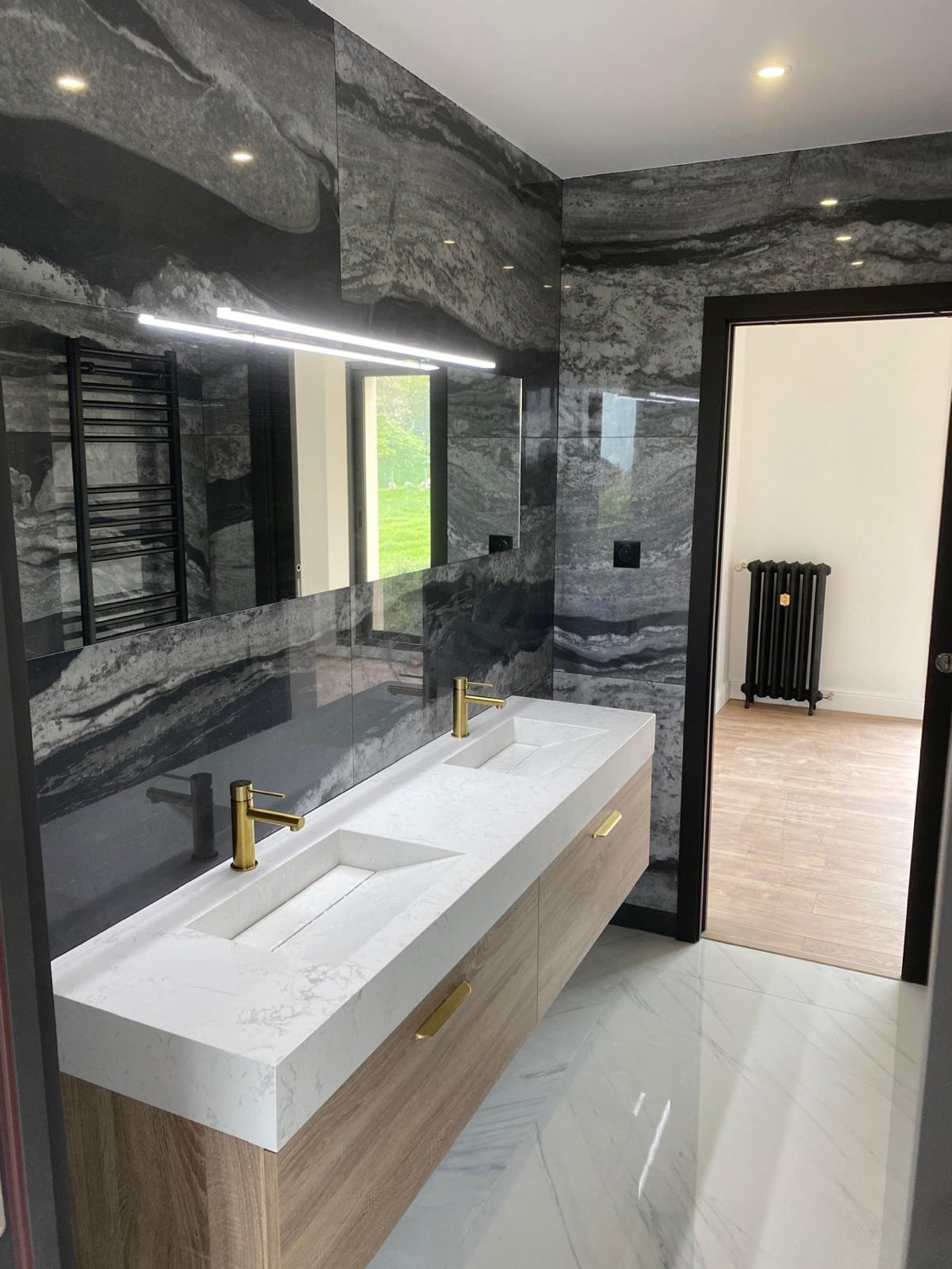 Salle d'eau en marbre gris veiné avec double vasque blanche sur meuble bois