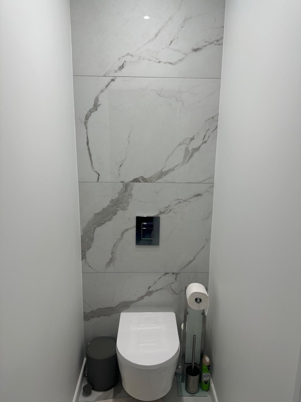 WC suspendu avec mur habillé de carrelage marbre blanc veiné toute hauteur et commande chromée — chantier à Pont-l'Évêque